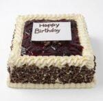 Egg-free Black Forest birthday cake with soft chocolate sponge, fresh dairy topping, chocolate curls around the sides, rich cherry glaze topping, personalised edible message plaque, and elegant piped border. Ideal for birthdays, anniversaries, and special occasions.