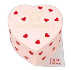 Pink heart anniversary cake with red heart decorations and custom message