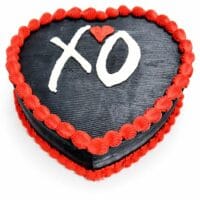 Top view of a heart-shaped black fresh cream cake with red borders and a personalised XO design.