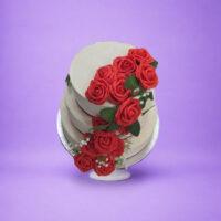 Luxury Egg Free wedding cake featuring three tiers with handcrafted red rose cascade decoration.