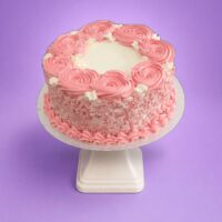 Egg Free pink rosette celebration cake with textured cream sides, pink decorative swirls and space for a personalised message.