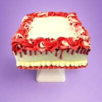 Egg Free square celebration cake with a red drip finish, red and white decorative swirls, and space for a personalised message.