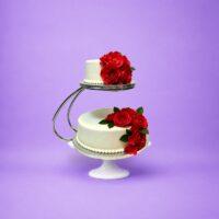 Luxury two-tier fresh cream wedding cake with red rose floral decoration on floating cake stand