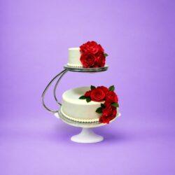 Luxury two-tier fresh cream wedding cake with red rose floral decoration on floating cake stand