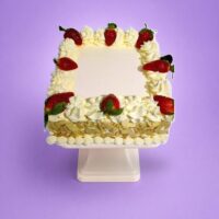 Egg-free strawberry celebration cake decorated with fresh strawberries, smooth vanilla cream, almond flake sides and space for a personalised message.