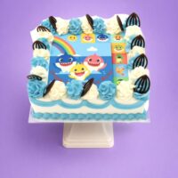 Baby Shark photo birthday cake with edible image, blue and white fresh cream rosettes, and chocolate leaf decorations