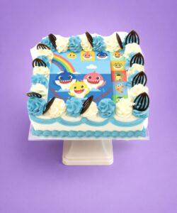 Baby Shark photo birthday cake with edible image, blue and white fresh cream rosettes, and chocolate leaf decorations