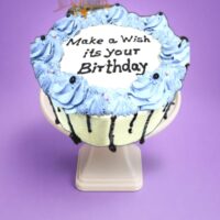 stylish Egg Free Blue Chocolate Drip Birthday Cake decorated with blue piping, chocolate drip, edible pearls and a personalised cake topper. Freshly made to order in Sheffield for birthdays and special celebrations.