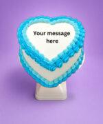 Blue heart-shaped birthday cake with smooth white icing, vibrant blue piped borders, and space for a personalised celebration message.