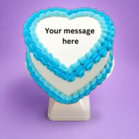 Blue heart-shaped birthday cake with smooth white icing, vibrant blue piped borders, and space for a personalised celebration message.