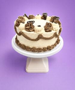 Classic Chocolate & Vanilla Celebration Cake decorated with smooth vanilla buttercream, chocolate buttercream swirls, elegant chocolate piping, chocolate decorations, and a plain centre for a personalised message. Freshly made in Sheffield.