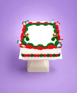 Square Christmas buttercream cake with Santa decorations and smooth white icing.