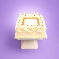 Square fresh cream celebration cake with smooth piped cream icing, rainbow sprinkles border, classic jam dots, decorative cream swirls, and space for a personalised birthday or celebration message, handmade by Cake Palace UK.