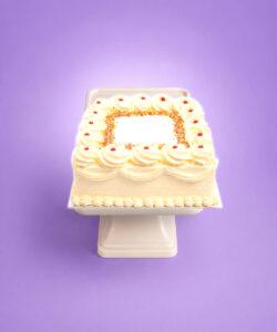 Square fresh cream celebration cake with smooth piped cream icing, rainbow sprinkles border, classic jam dots, decorative cream swirls, and space for a personalised birthday or celebration message, handmade by Cake Palace UK.
