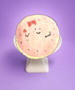 Round pink tooth-themed birthday cake with adorable tooth character and personalized message