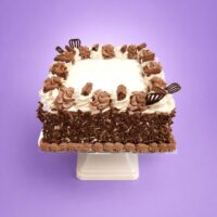 Square egg-free chocolate celebration cake decorated with fresh dairy topping, chocolate piping, premium chocolate curls covering the sides, chocolate curl pieces, decorative chocolate fans, and a large space for a personalised edible birthday message.