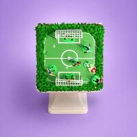 Egg-free football pitch birthday cake decorated with an edible football field, player figures, goalposts and grass-effect piping.