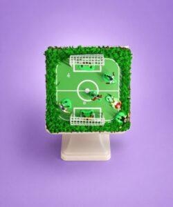 Egg-free football pitch birthday cake decorated with an edible football field, player figures, goalposts and grass-effect piping.