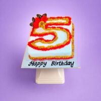 Egg-free number 5 birthday cake decorated with red and gold cream piping, floral decorations and chocolate accents.