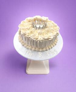Elegant Ivory Crown Wedding Cake with ivory fresh cream rosettes, silver crown topper, egg-free vanilla or chocolate sponge from Cake Palace.