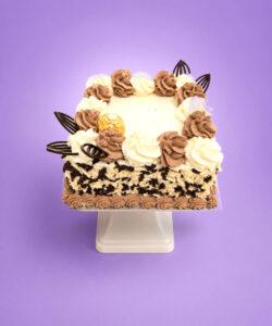 Ferrero Rocher & Chocolate Flake Celebration Cake with vanilla and chocolate buttercream swirls, white and dark chocolate flakes around the sides, Ferrero Rocher chocolates, and elegant dark chocolate decorations. Freshly made by our Sheffield bakery.