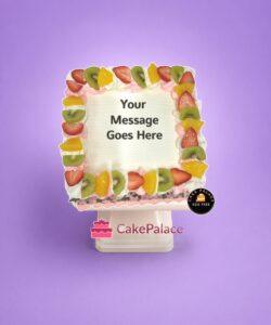 Egg-free fresh fruit fresh cream cake topped with strawberries, kiwi, pineapple, and personalised message