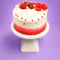 Top view of Tall Strawberry & Rose Celebration Cake with fresh strawberries, handcrafted red cream roses, elegant red and gold sugar pearls, and smooth fresh cream finish.