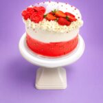 Luxury Tall Strawberry & Rose Fresh Cream Cake decorated with smooth white and red ombre fresh cream, handcrafted fresh cream roses, fresh strawberries, delicate white flowers, and gold sugar pearls. Freshly made in Sheffield.
