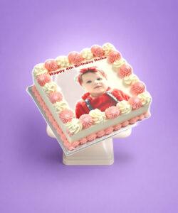 Personalised square birthday cake with a custom edible photo printed on top, finished with pink and white piped swirls around the border, smooth white icing finish, and matching pink piped base trim. Ideal for birthdays, children's parties, anniversaries, baby celebrations, and personalised cake gifts.