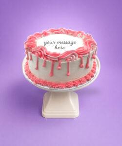 Round white fresh cream birthday cake with pink drip decoration, pink piped borders, textured sides, and a personalised message.