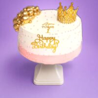 Pink and gold princess crown birthday cake decorated with a luxury gold crown topper, gold spheres, edible pearl details and personalised birthday message.