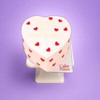 Pink heart anniversary cake with red heart decorations and custom message