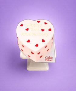 Pink heart anniversary cake with red heart decorations and custom message