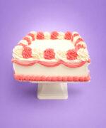 Pink and white square celebration cake with smooth vanilla cream frosting, alternating pink and white buttercream swirls, decorative pink wave piping around the sides, matching pink shell border, and a large blank centre ready for a personalised edible image or custom message.