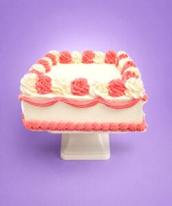 Pink and white square celebration cake with smooth vanilla cream frosting, alternating pink and white buttercream swirls, decorative pink wave piping around the sides, matching pink shell border, and a large blank centre ready for a personalised edible image or custom message.